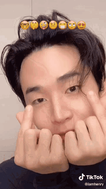 a man is making a heart with his fingers and has emojis on his head