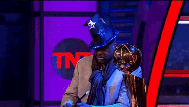 a man holding a trophy in front of an tnt logo