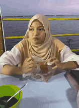 a woman wearing a hijab is sitting at a table eating food .