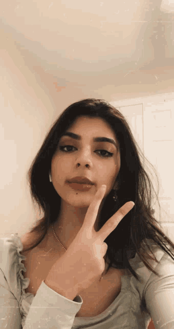 a woman is making a peace sign with her hand