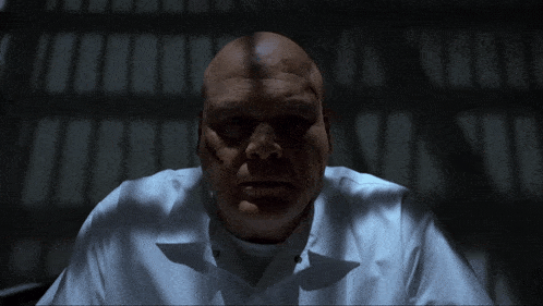 a bald man in a white shirt is in a dark room