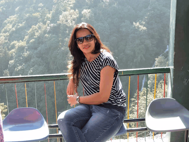 a woman wearing sunglasses sits on a chair in front of a fence