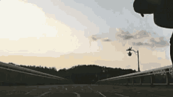 a person is standing on a bridge with a street light in the distance .