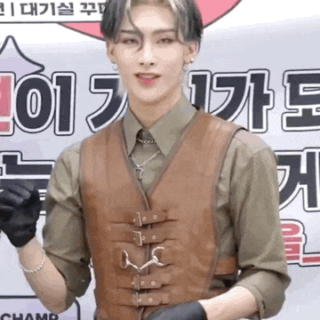 a young man wearing a brown vest and black gloves