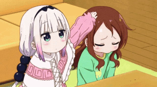a girl is petting another girl 's head with a blanket