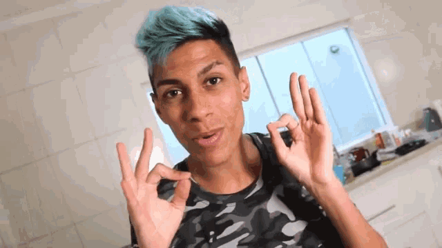 a young man with blue hair and a camouflage shirt is giving the ok sign