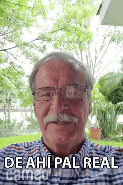 an older man with glasses and a mustache is smiling and looking at the camera .