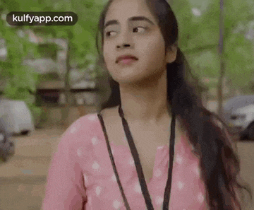 a young woman wearing a pink shirt and a lanyard around her neck .