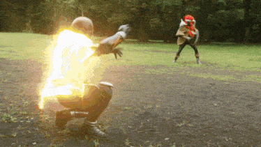 a man in a superhero costume is kneeling down in a field with a glowing light behind him