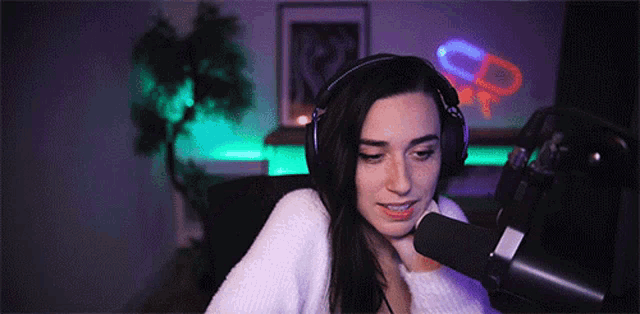 a woman wearing headphones is sitting in front of a microphone in a dark room .