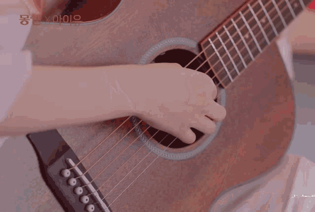 a close up of a woman holding a guitar with korean writing on the bottom left