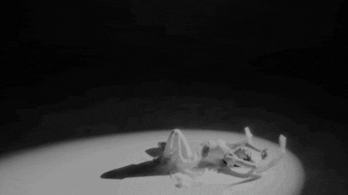 a black and white photo of a woman laying on the floor in a spotlight