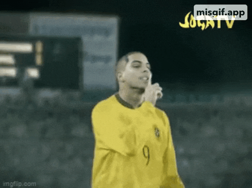 a man in a yellow shirt with the number 9 on it is holding a microphone in his hand .