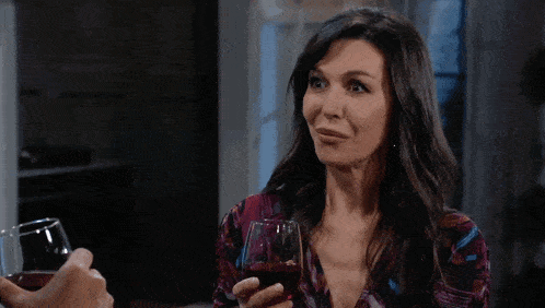 a man holding a glass of wine talks to a woman in front of a painting of birds