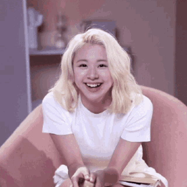 a woman with blonde hair is sitting in a chair and smiling .