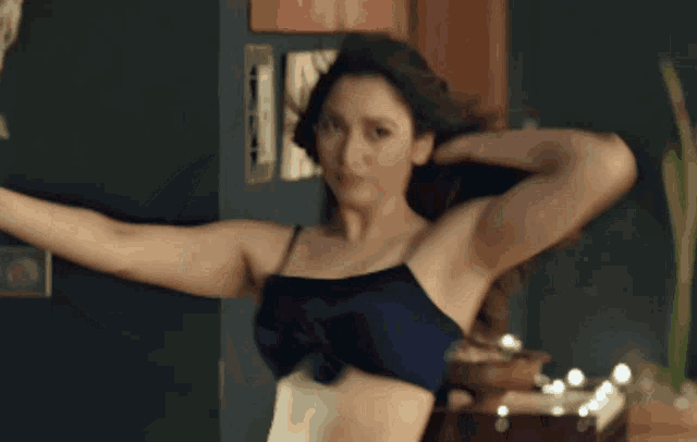 a woman in a black bra is dancing in front of a door