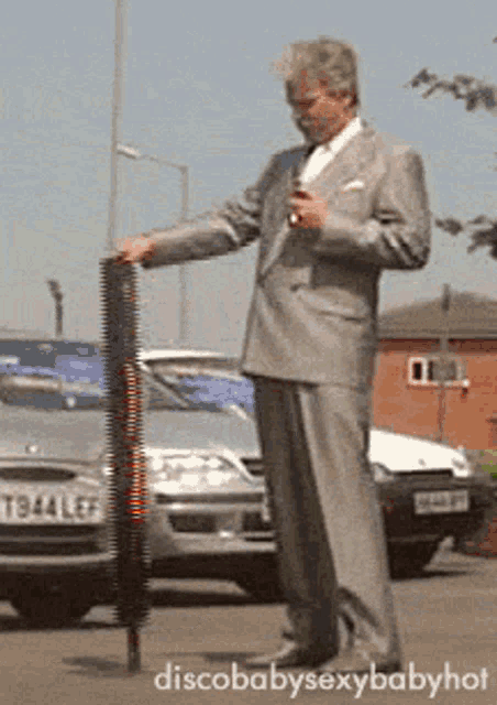 a man in a suit is holding an umbrella in front of a car with a license plate that says tb44 lef