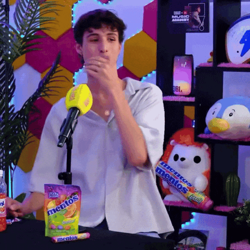 a man is holding a bag of mentos candy in front of a microphone