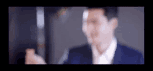 a blurry picture of a man in a suit looking at a cell phone .
