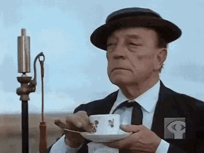 an older man in a suit and hat is holding a cup of coffee .