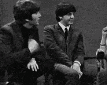 a black and white photo of three men sitting next to each other on a stage .