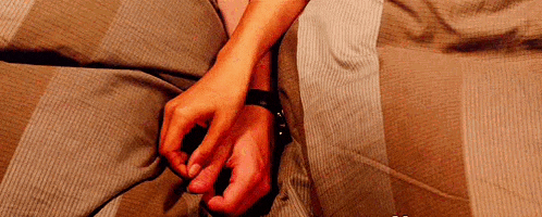 a woman is holding a man 's hand while laying on a bed .