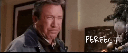 a man is crying in front of a christmas tree while standing in front of a fireplace .