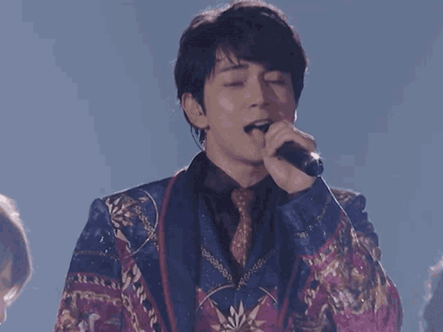 a man singing into a microphone while wearing a colorful suit