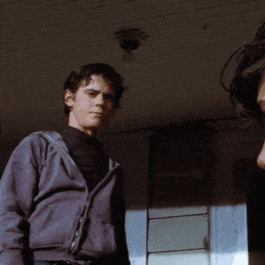 a man in a hoodie is standing on a porch with a woman