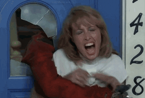 a woman is screaming in front of a blue door with the number 428 written on it