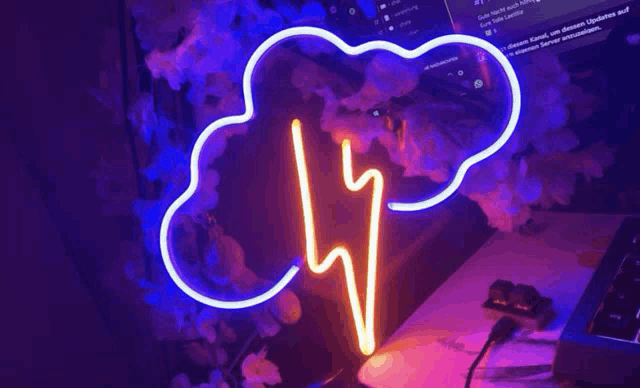 a neon sign in the shape of a cloud and lightning bolt is sitting on a desk .