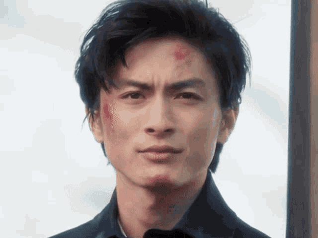 a close up of a man 's face with a red spot on his forehead
