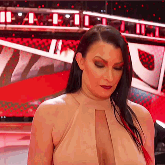 a woman in a tan dress is standing in front of a red background .