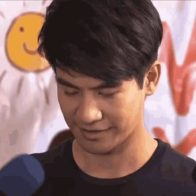 a close up of a man 's face with his eyes closed and a smiley face in the background .