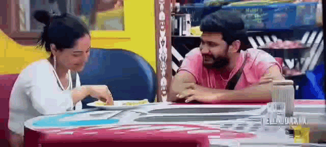 a man and a woman are sitting at a table with plates of food on it .