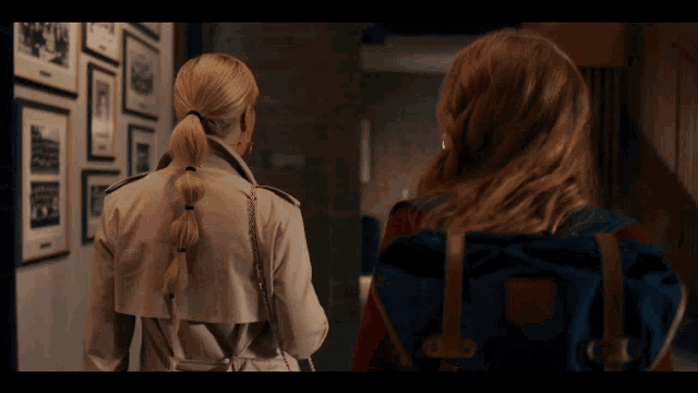 a woman in a trench coat stands next to another woman