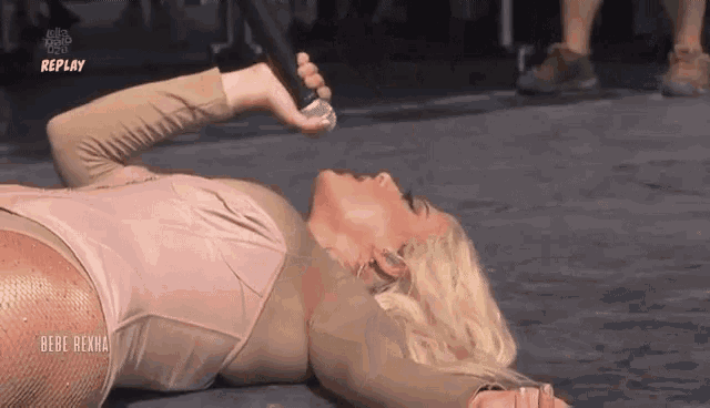 a woman is laying on the floor while holding a microphone in her hand .