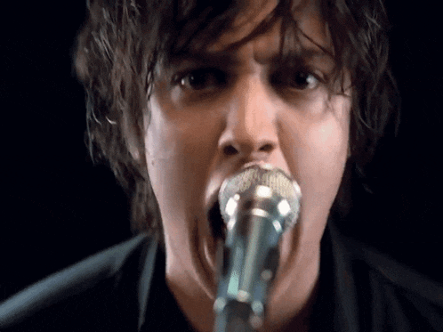 a man is singing into a microphone with his mouth open
