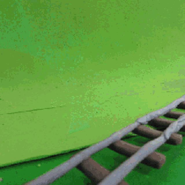 a toy train on a green background with smoke coming out of the engine