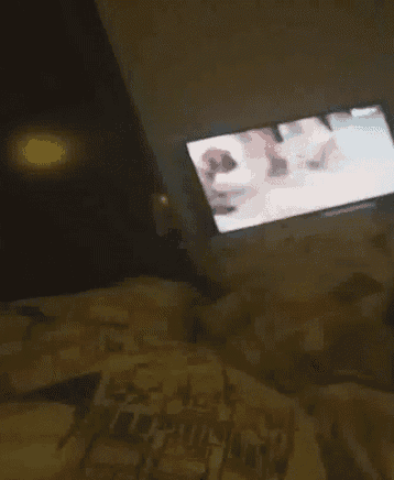 a person is laying on a bed in front of a tv .