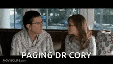 a man and a woman are sitting on a couch with the words paging dr cory written below them