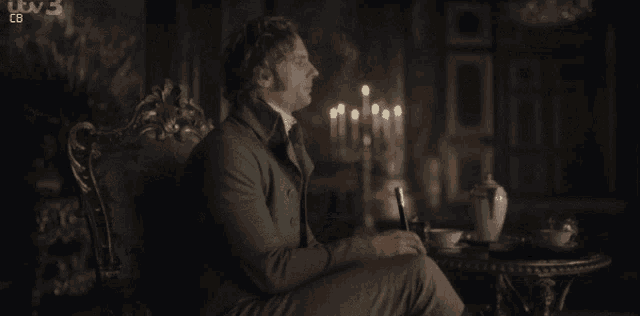 an older woman sits in a chair in front of a table with candles and a sign that says itv 3