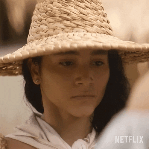 a woman wearing a straw hat with a netflix logo on the bottom