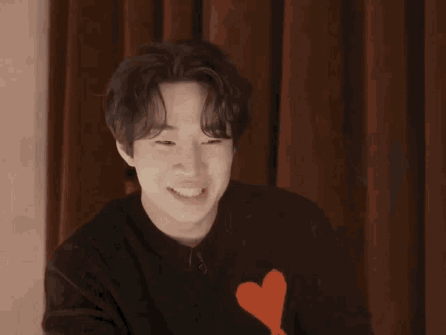 a young man wearing a black sweater with a red heart and the letter a on it