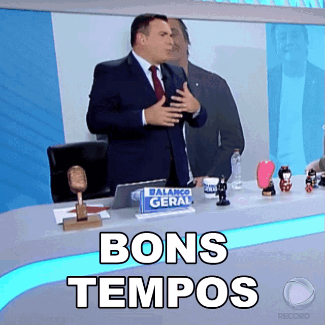a man sitting at a desk with a sign that says bons tempos on it