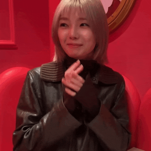 a woman covering her mouth with her hands in front of a red background