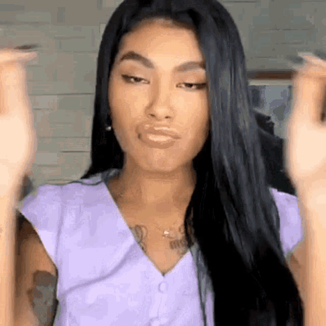 the woman is wearing a purple shirt and making a funny face .