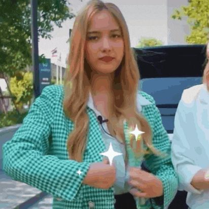 a woman in a green jacket is standing next to a woman in a white shirt .