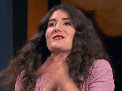 a woman with long brown hair is clapping her hands