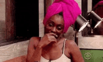a woman with a pink towel wrapped around her head is sitting on a couch .